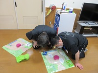 指導員が模擬キット（人の絵）の症状を確認しています。