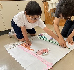 台紙に貼ったリボンの長さを確かめている写真。