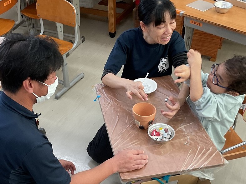 児童が講師先生と一緒にタイルを貼ろうとしている様子