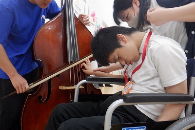 中学部の生徒が、コントラバスを触って観察している写真。