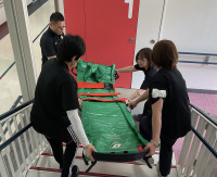 エアーストレッチャーを階段で運ぶ教員
