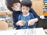 先生と一緒に土ねんどをちぎってみる幼児