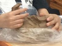 かたまりの土ねんどをちぎり取る様子