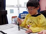 幼児が筆先をよく見ながら筆先を半紙にトントン押し付けている姿
