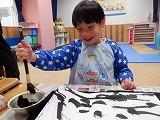 幼児が墨液を筆につけようとしているところ