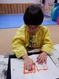 幼児が朱墨液をつけてスタンプを押しているところ