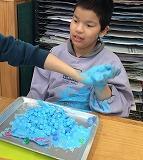児童がキューブ型の粘土や綿が混ざったクリーム粘土を手のひらに載せている写真。